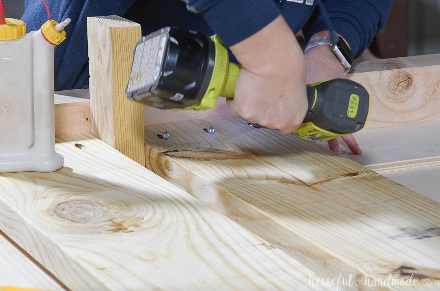 Fastening the 2x8 boards to the 4x4 legs with pocket holes while using a 2x4 block as a spacer. 
