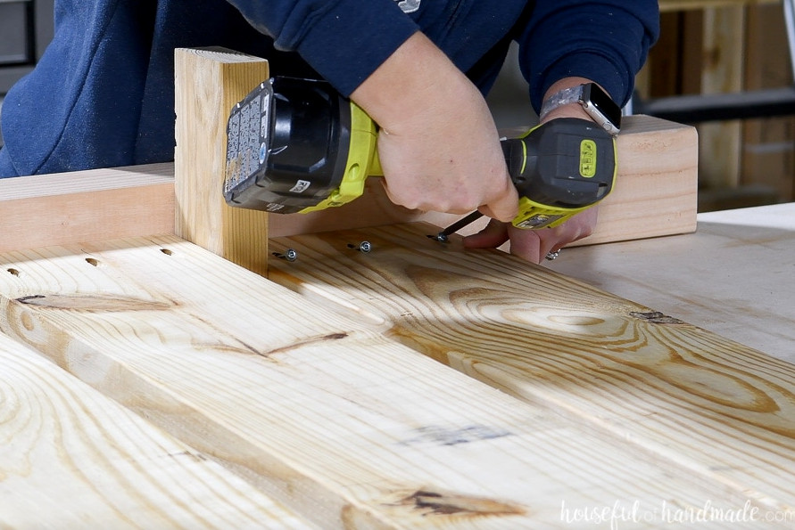 Fastening the bottom 2x8 board so it aligns flush with the front of the leg board. 