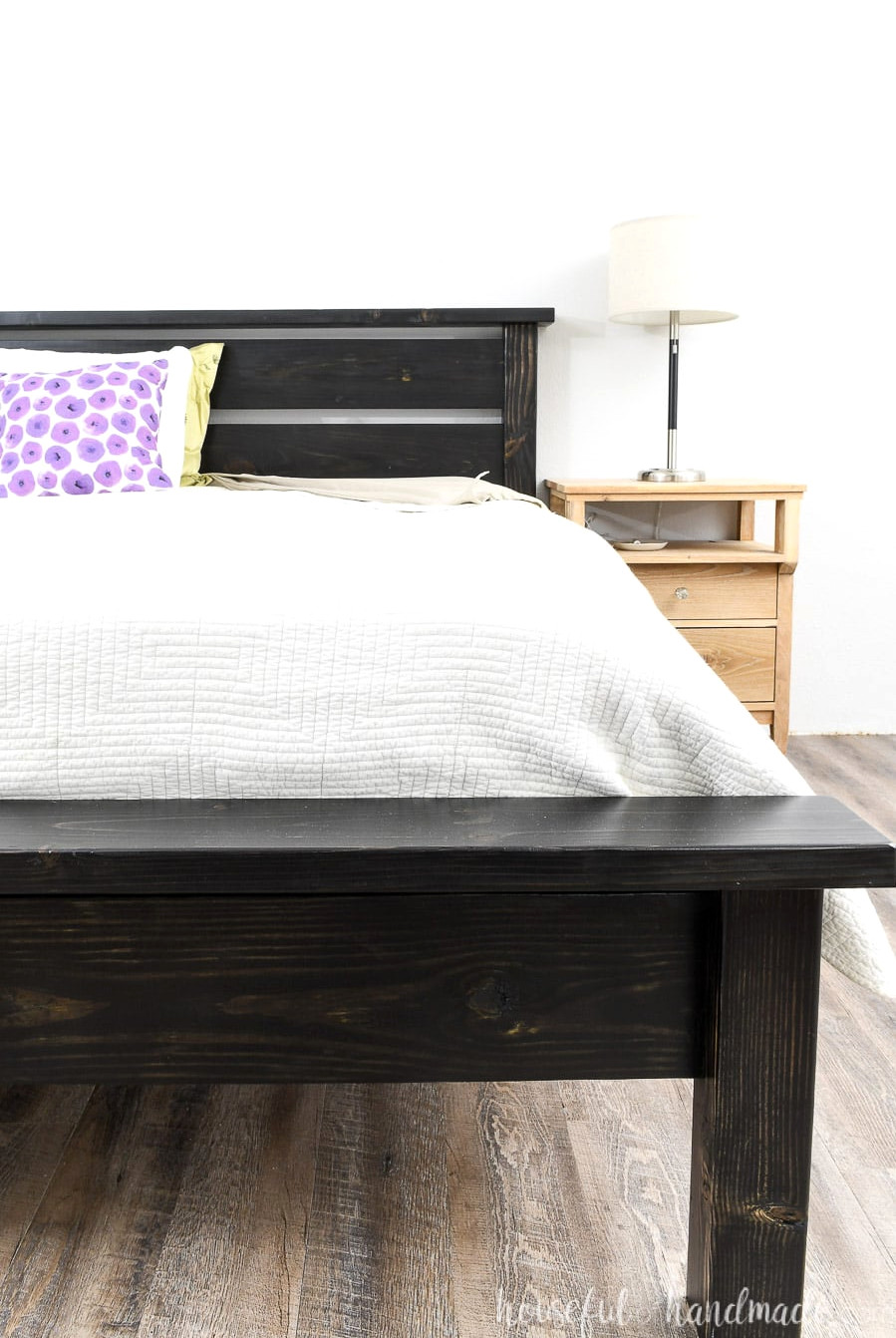 DIY platform bed frame that looks like a traditional bed sitting next to a nightstand.