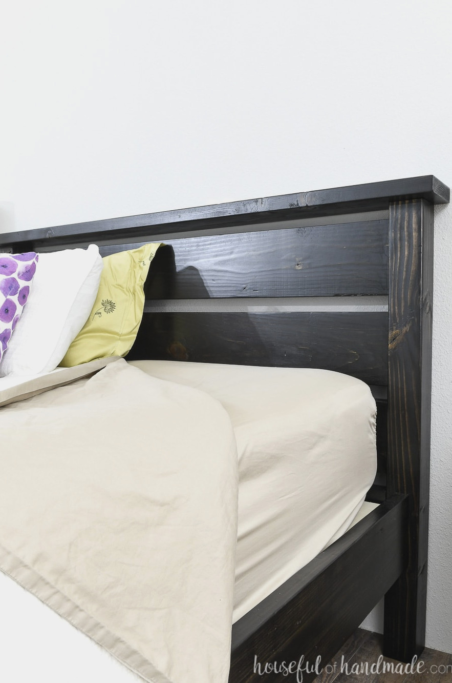 Detailed view of the black-stained headboard with the pillows pulled away from it. 