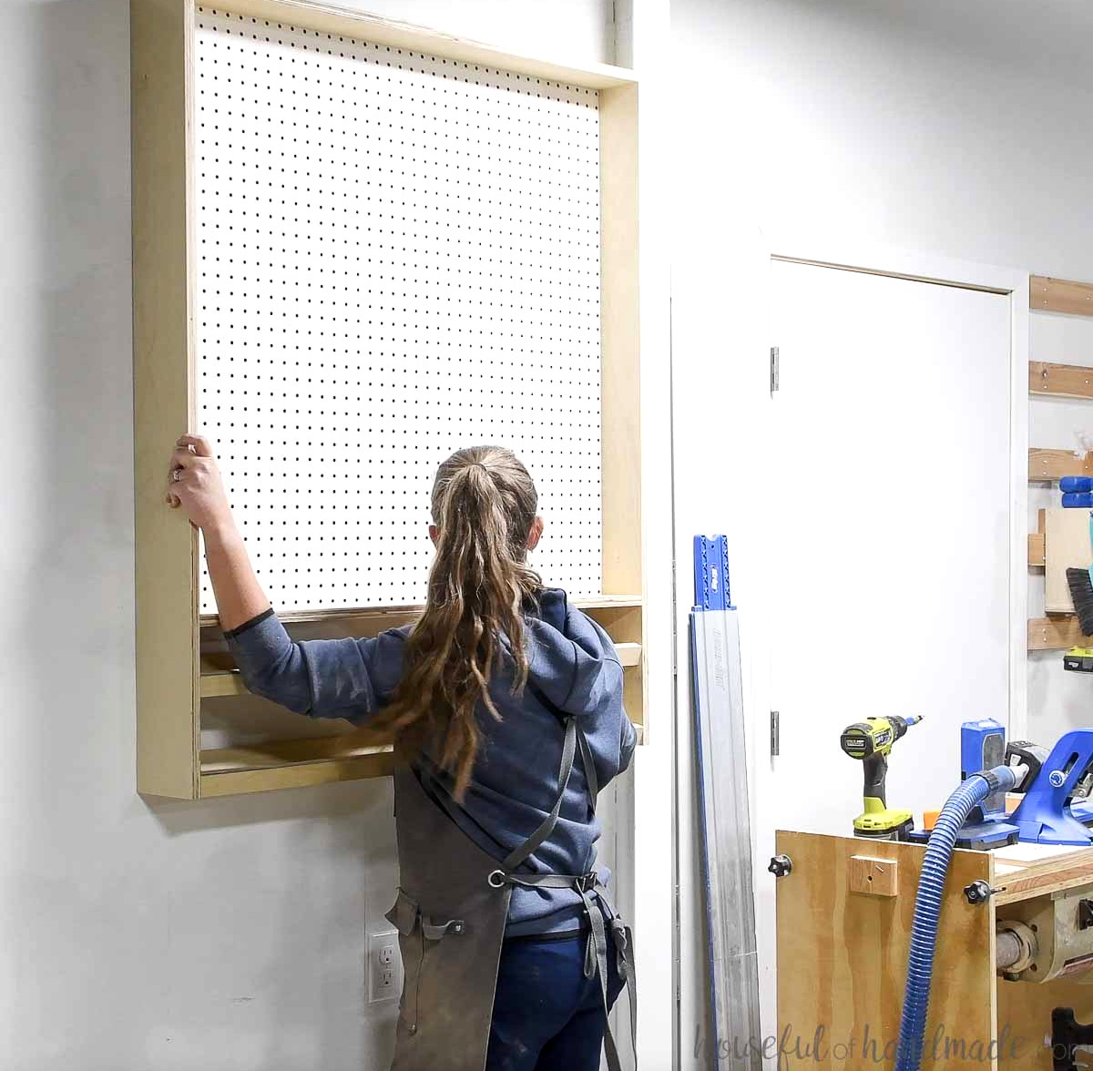 Kati hanging the finished pegboard storage cabinet on the wall