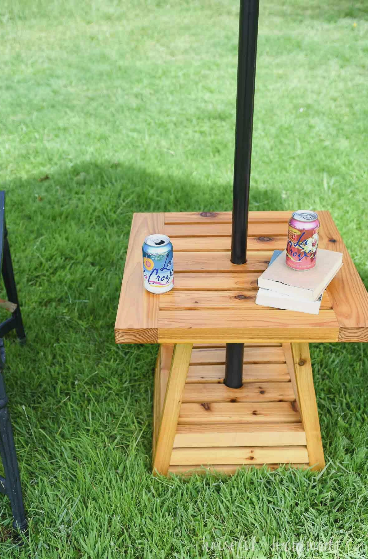 Looking down onto the top of the outdoor side table with a pyramid base and books and drinks on top of it.