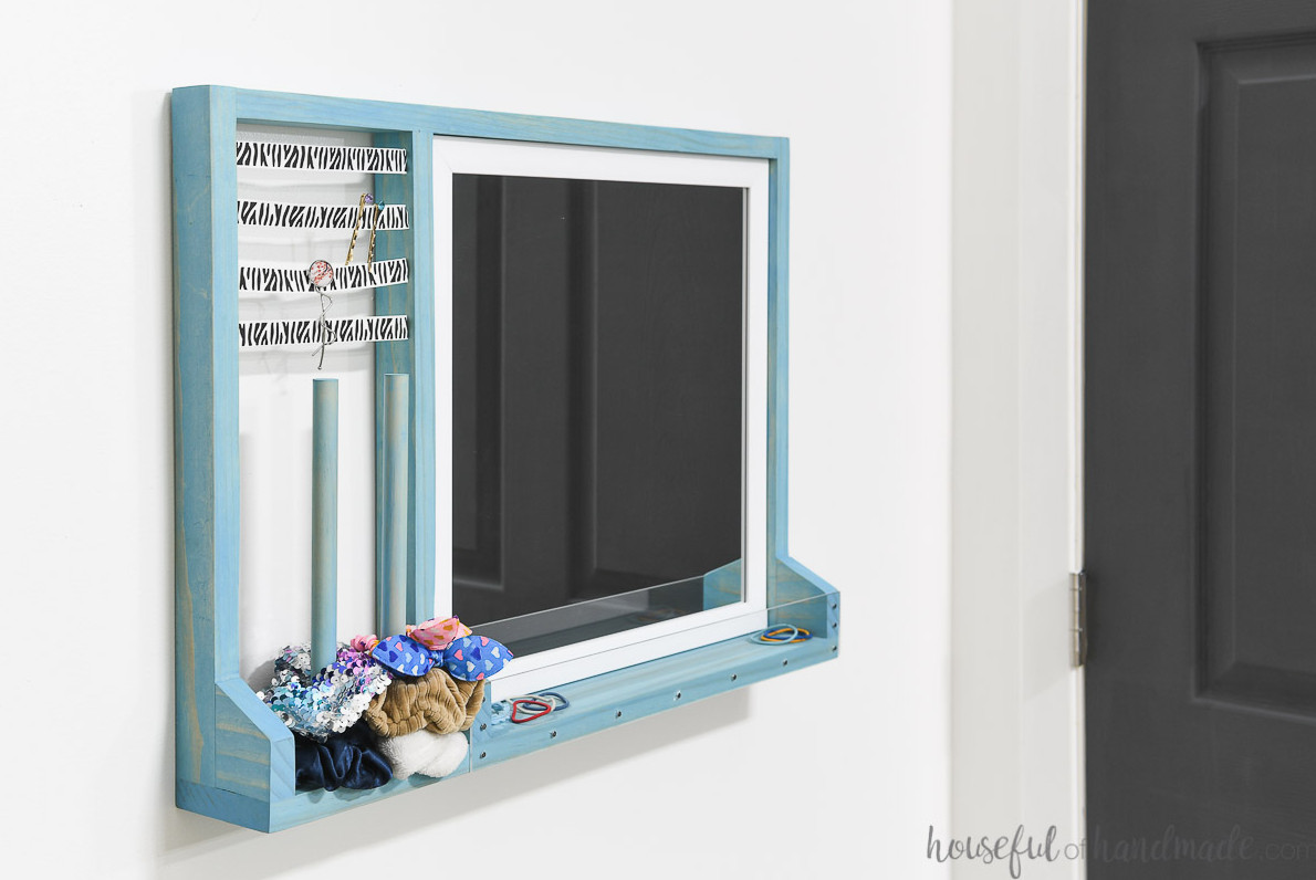 Hair accessory storage with a mirror hanging on a wall.