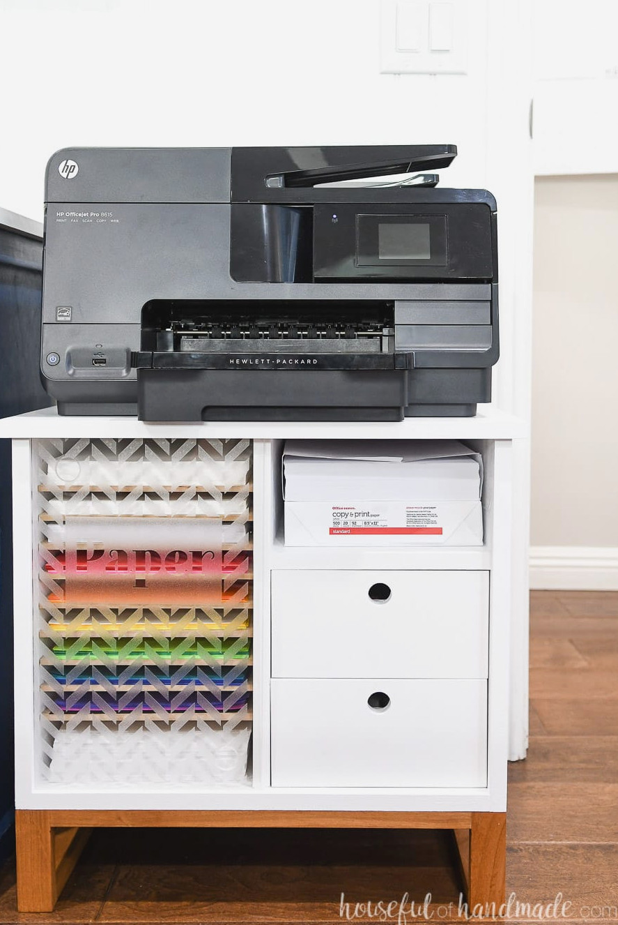 Compact white printer stand with a wooden base. Plenty of shelves for storing paper and 2 drawers.