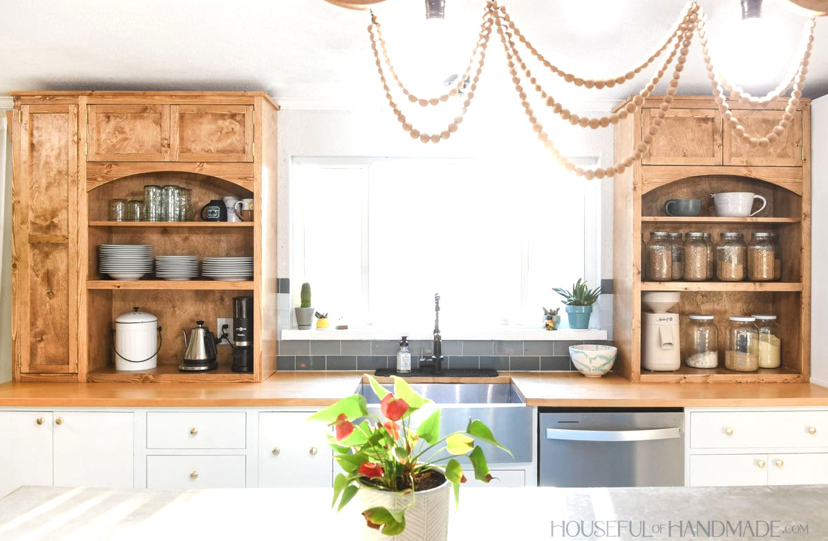 Kitchen featuring medium wood countertop cabinets on both sides of the sink, with a large window between them.