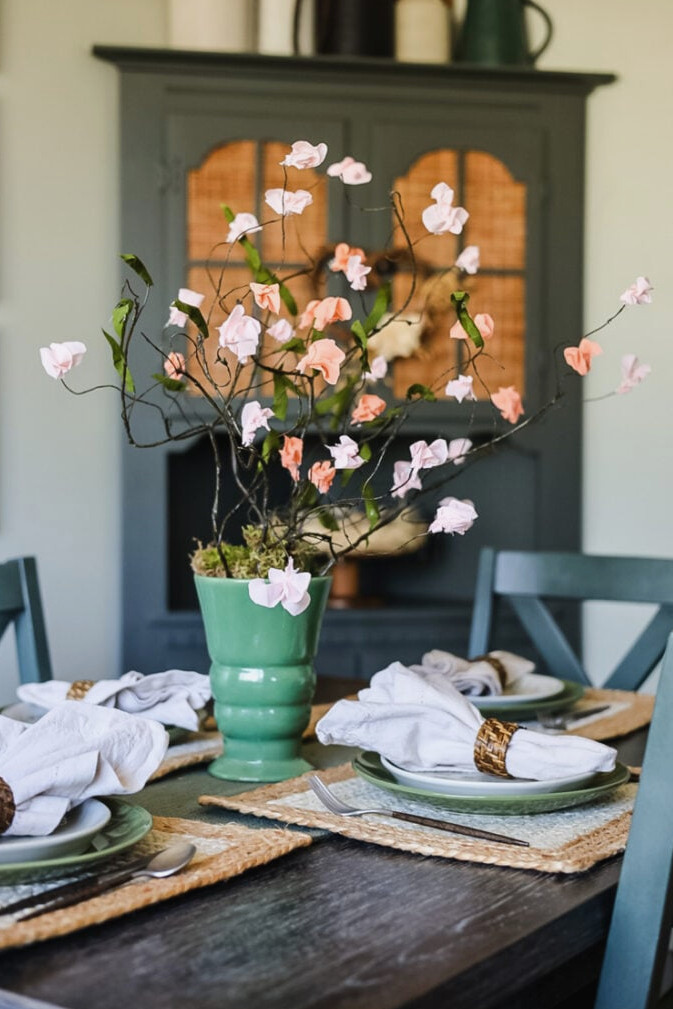 dining table with paper flowers in a green vase