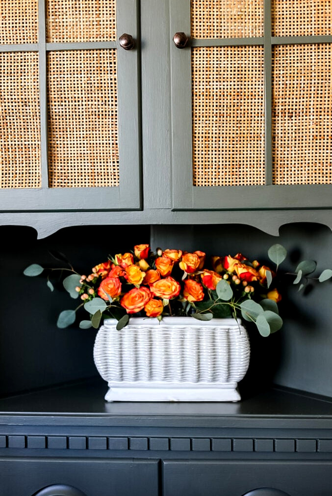 green hutch with orange rose display on shelf