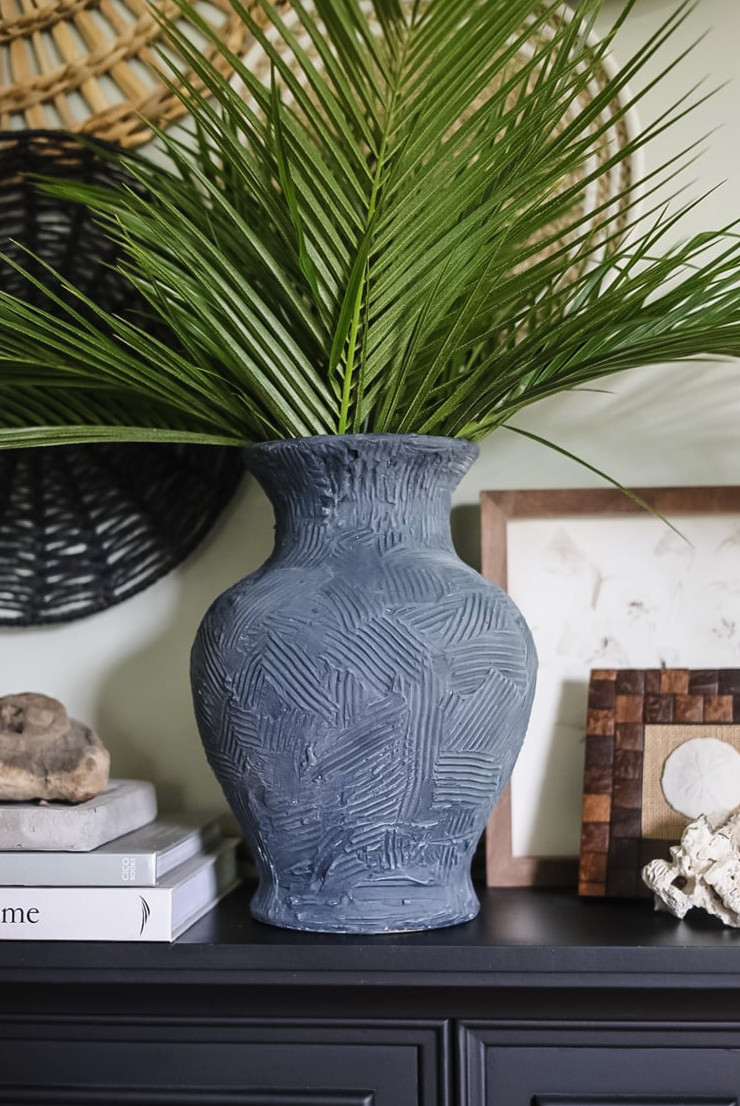 an indigo blue vase filled with tall palm fronds on a mantle